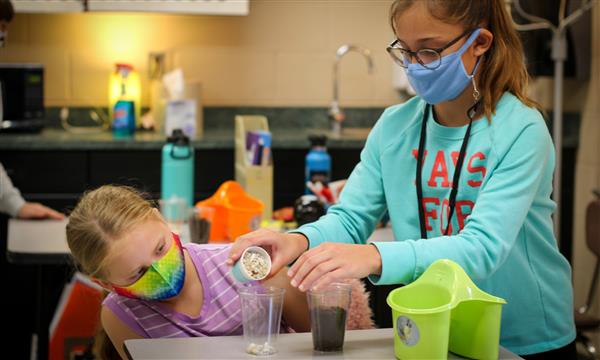 Students fill cups with gravel